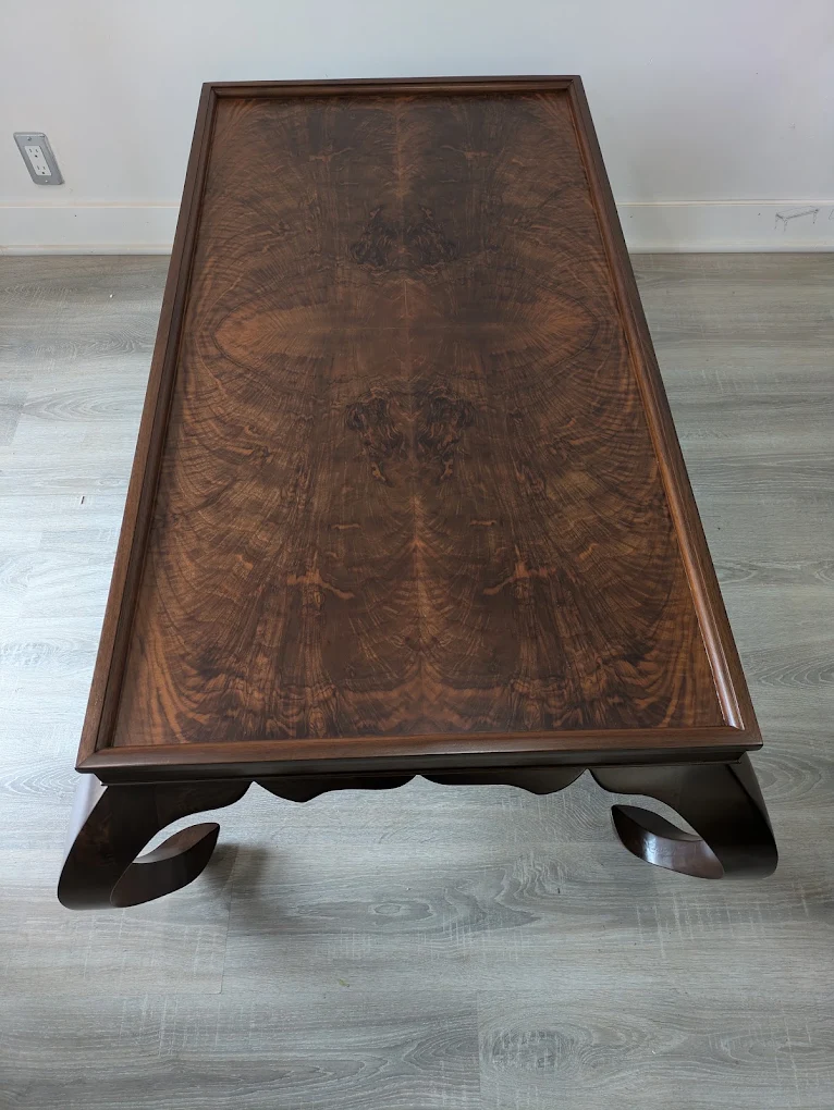 Top view of a coffee table with a book-matched burl walnut top showing mirrored flame figuring inside a raised walnut tray edge