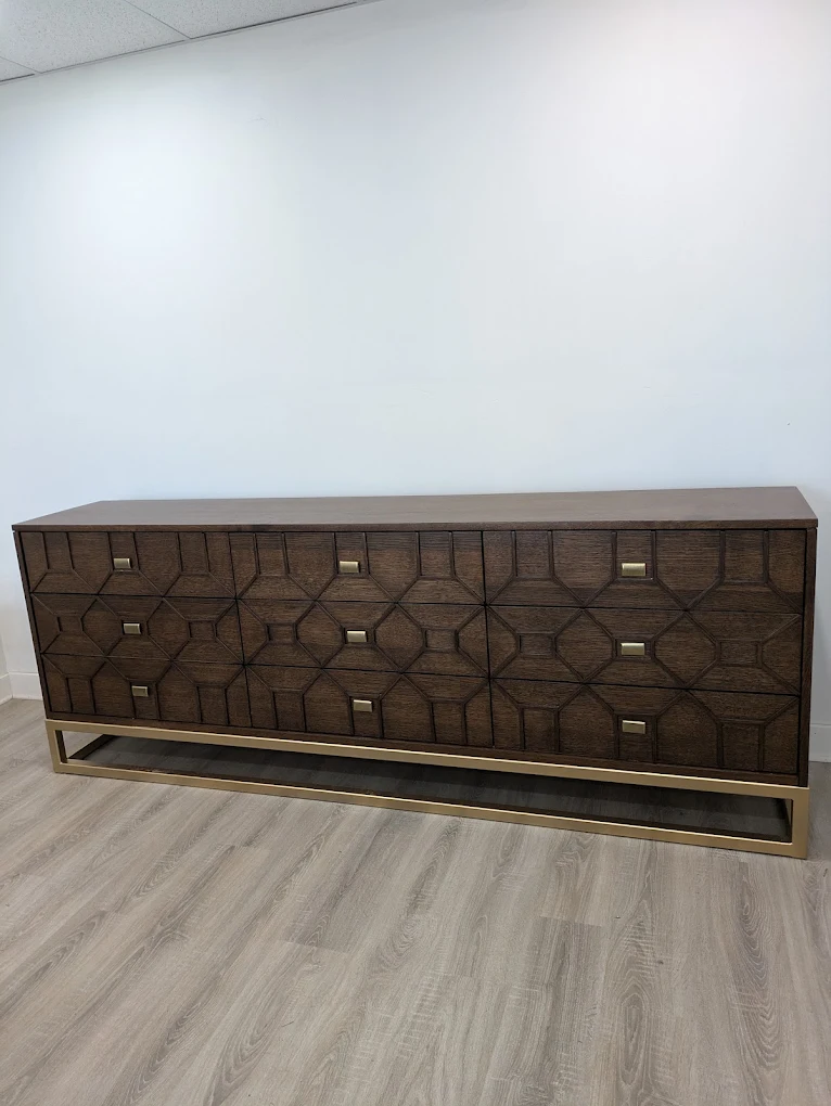 Long dark wood sideboard with a geometric drawer front pattern on a brass base